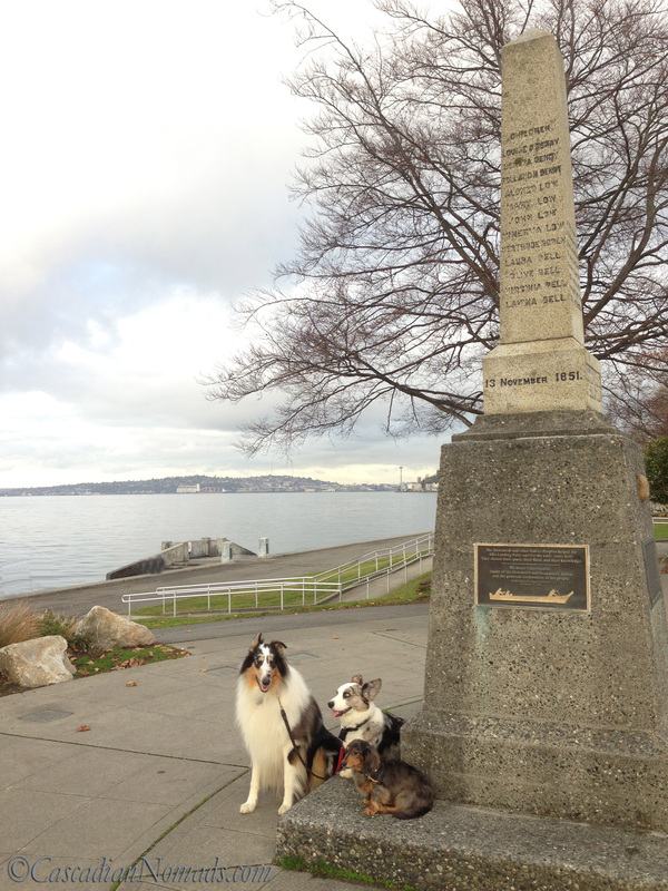 A Remarkable Seattle Site's Historic Monument Sounds Dull But There Are Dogs: collie, dachshund and corgi at the Denny Landing Monument with the Seattle Space Needle in view
